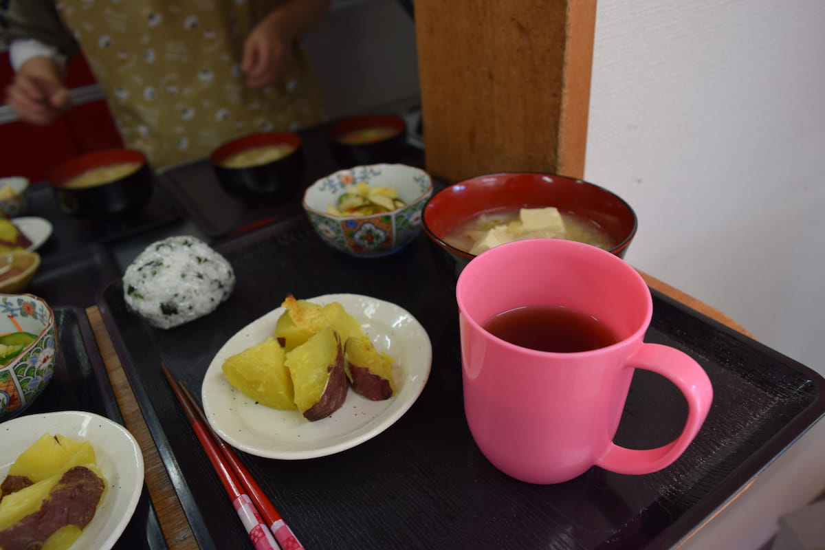 お盆の上に昼食と焼き芋を一人分ずつ乗せています。