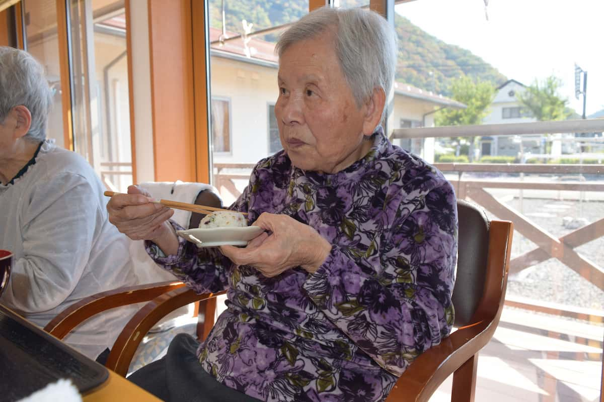 お皿の上に乗ったおにぎりをお箸で食べています。