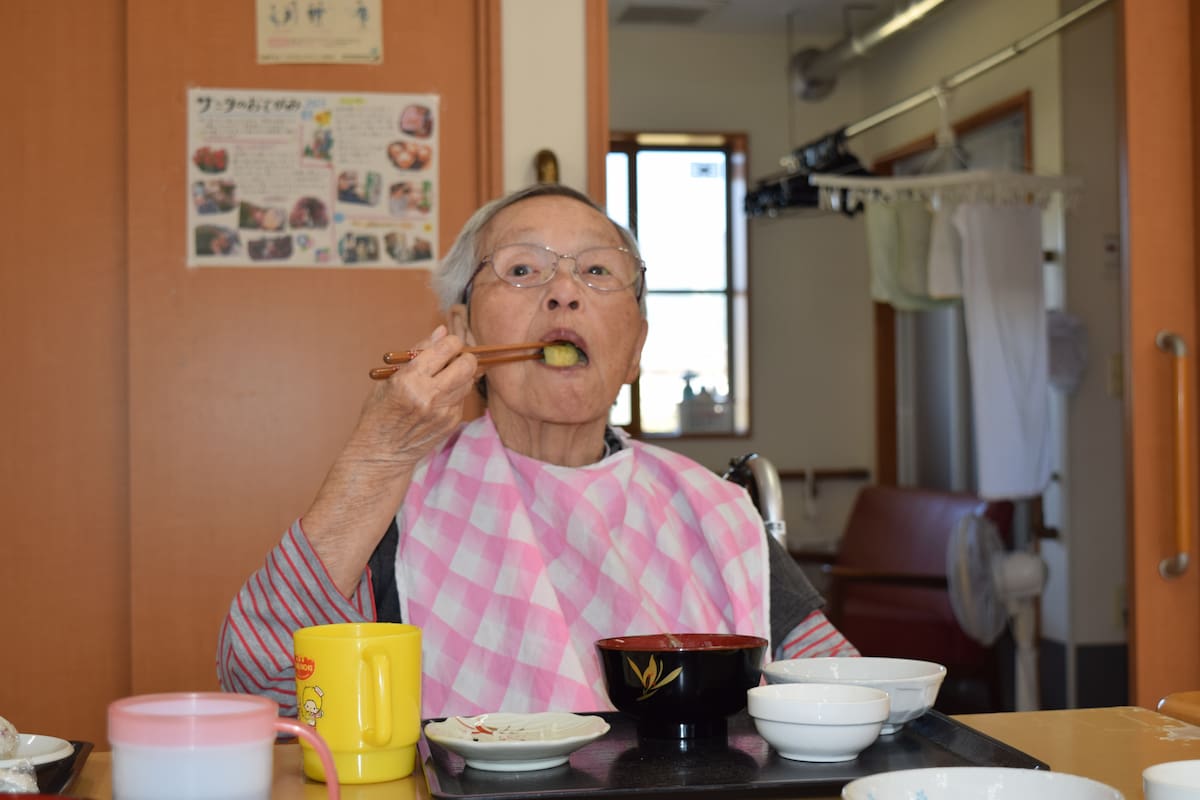 口を大きく開けて焼き芋をお箸で頬張っています。