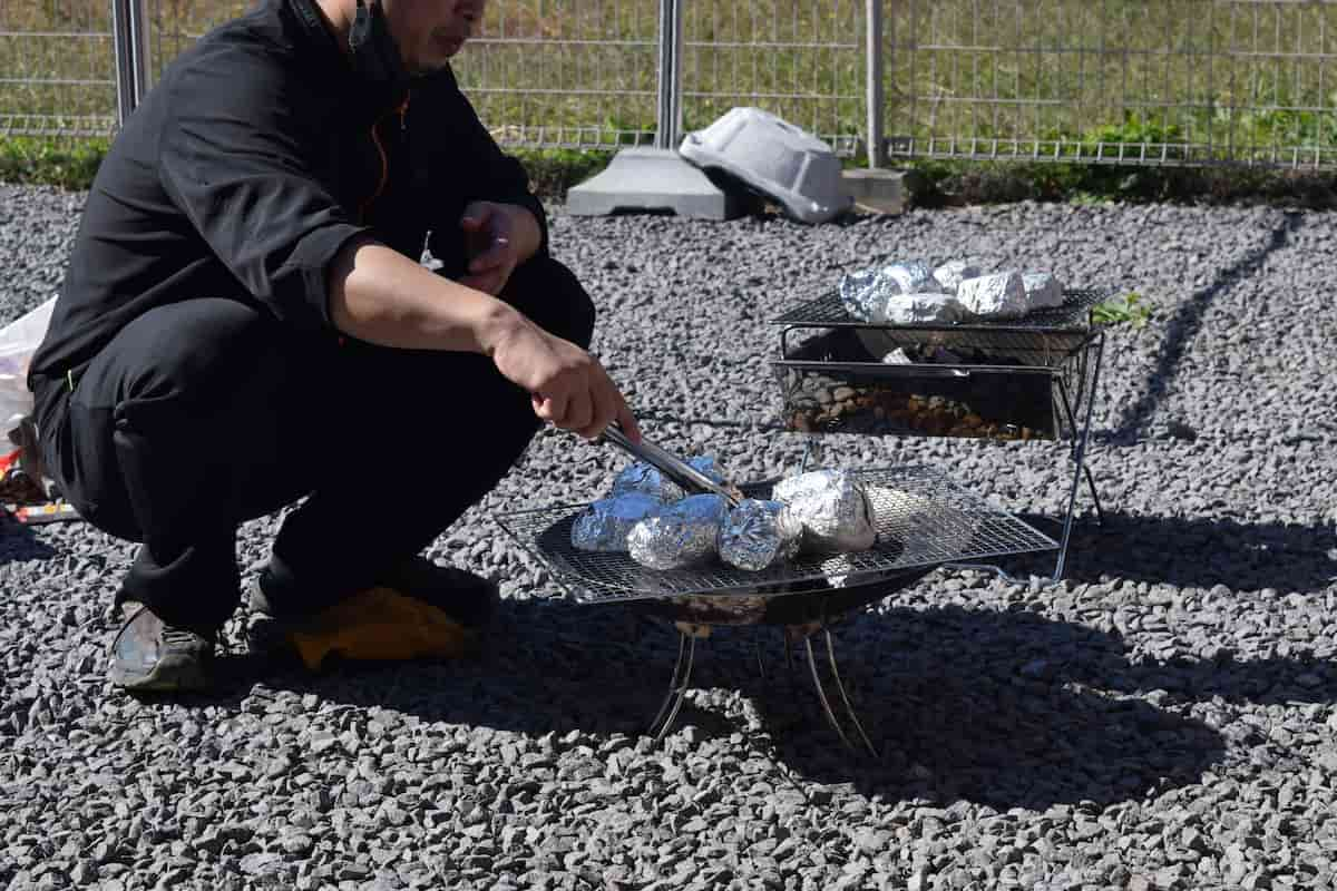 アルミホイルに包んだ焼き芋を屋外用のコンロで焼いています。