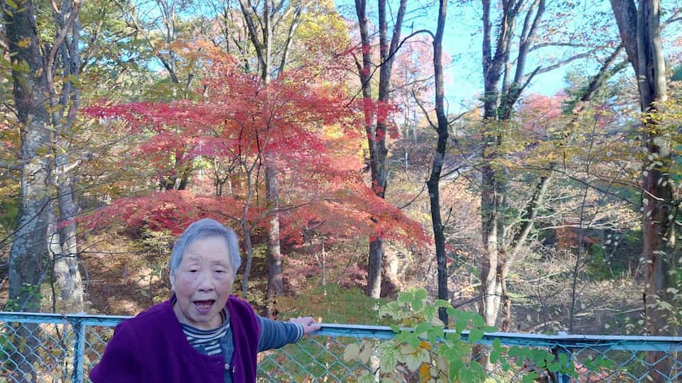 空、木立、紅葉を背景に入居者は満面の笑みです。