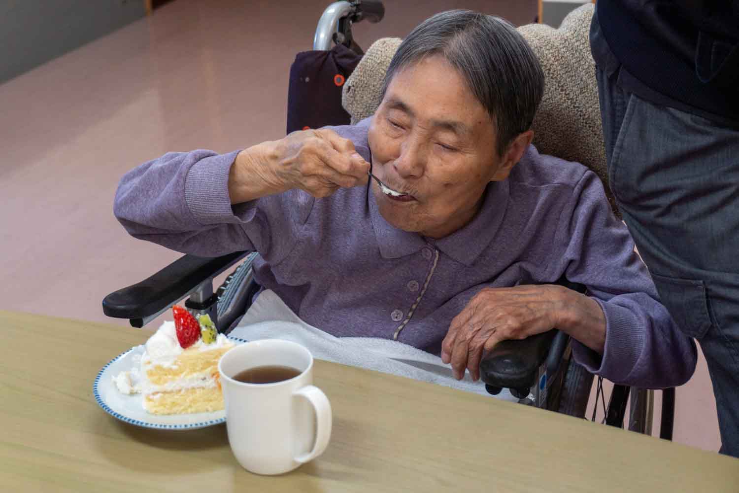 利用者さんがおいしそうにケーキをスプーンでほおばっています。