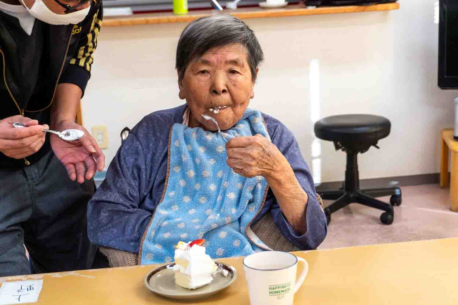 職員に介助されてケーキを食べています。