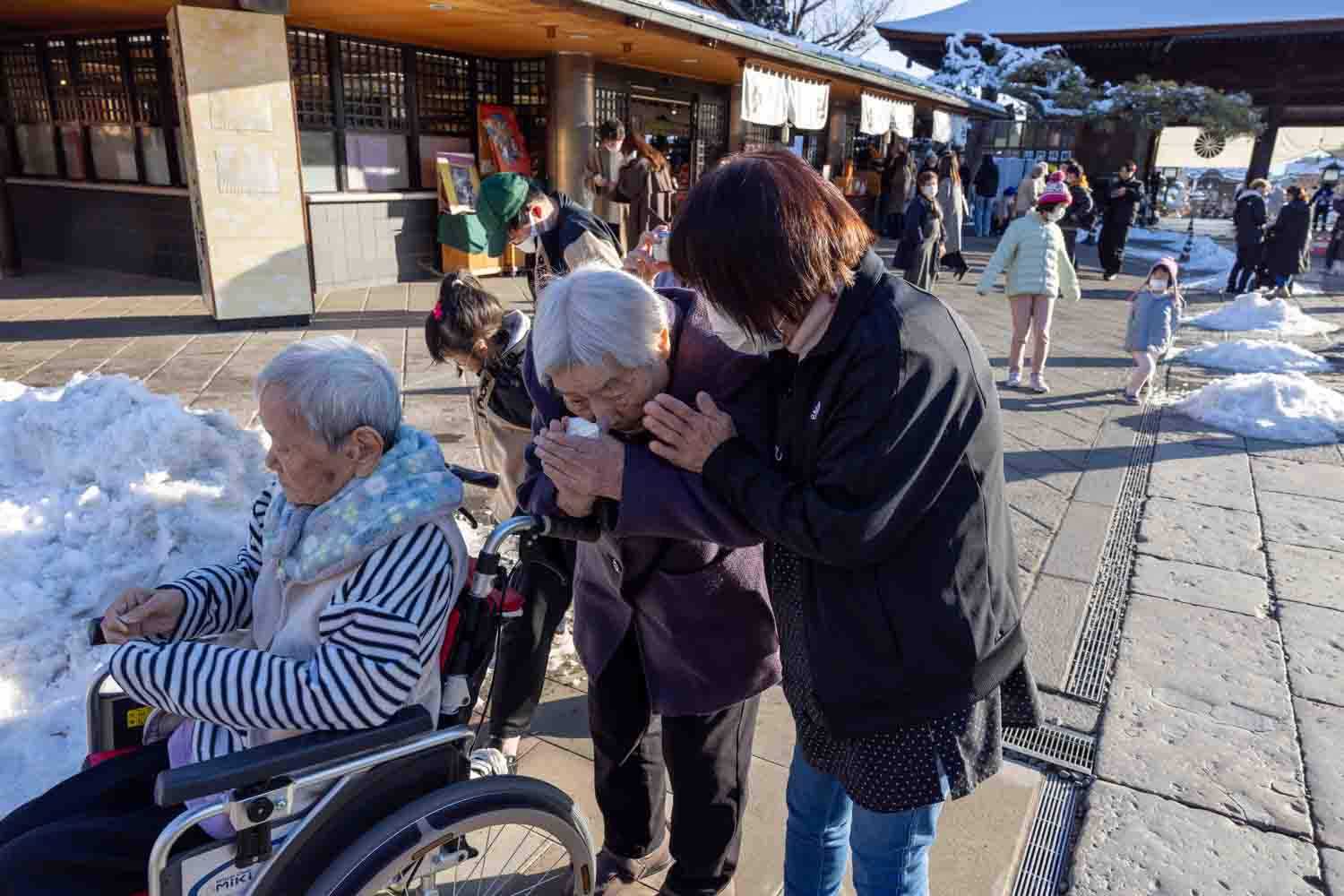 利用者さんと職員が一緒に本堂前でお祈りをしています。