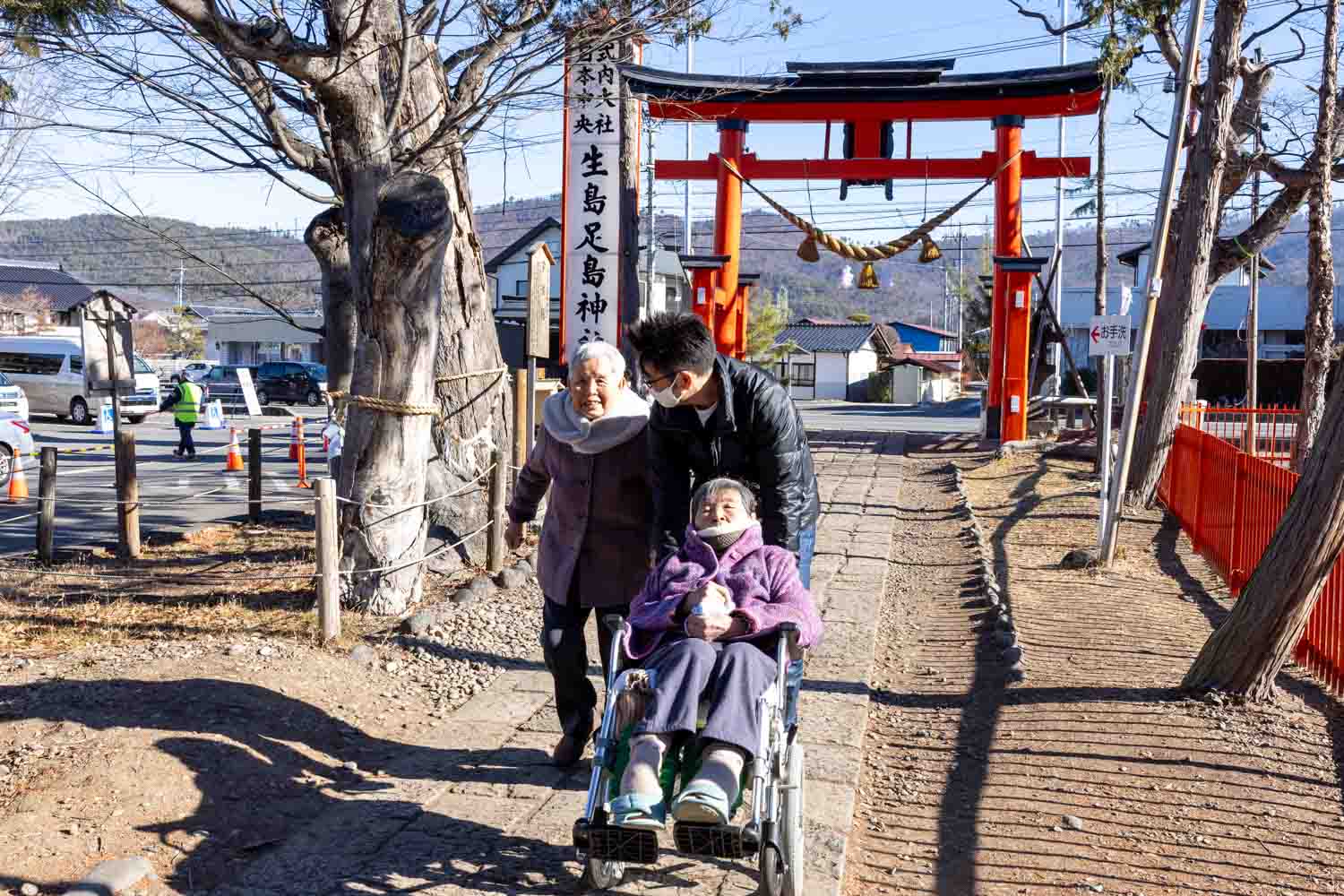 男性の職員が利用者さんの車いすを押しながら本殿に向かっています。