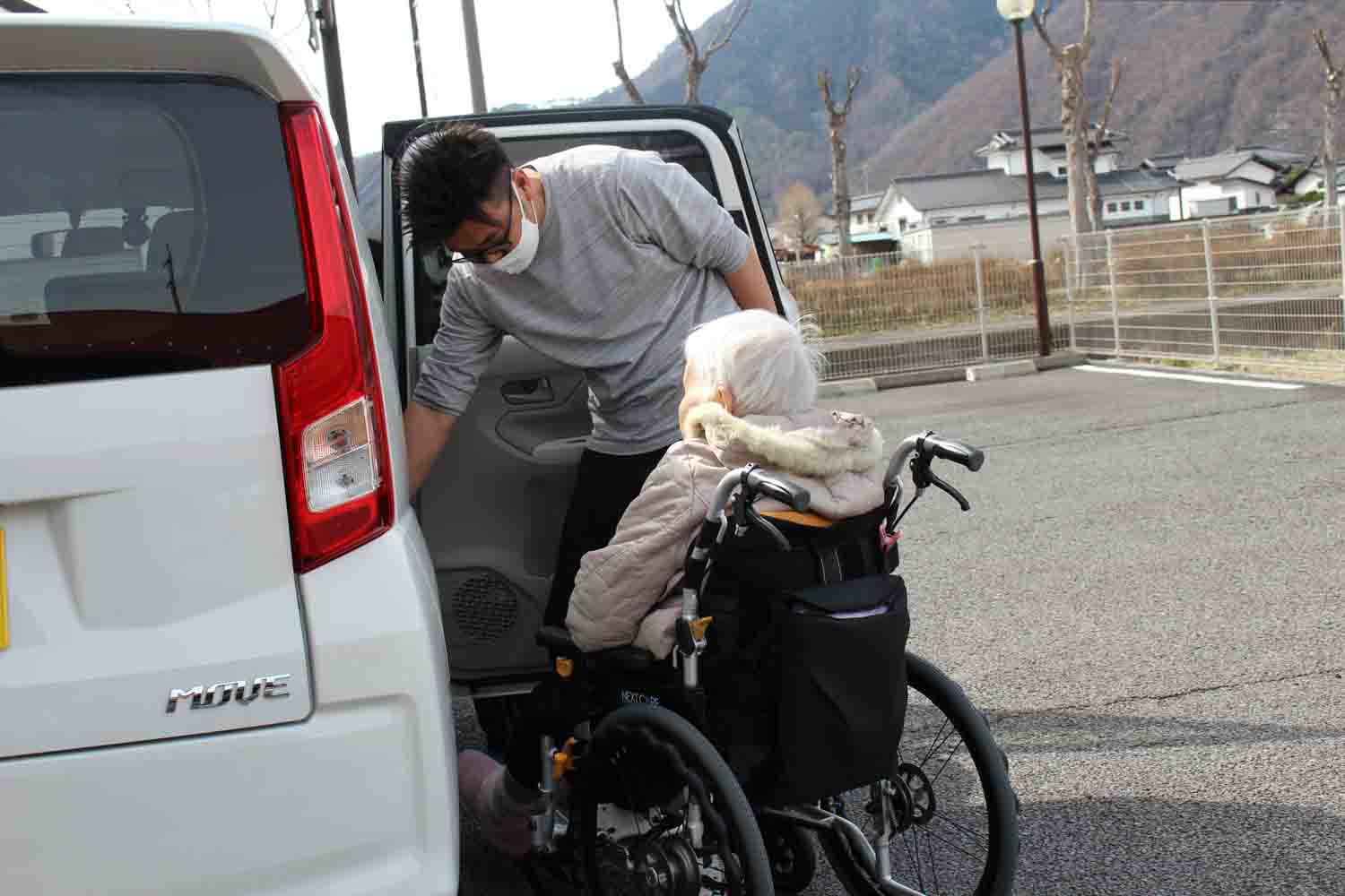 軽自動車の後部座席に利用者さんを乗せています