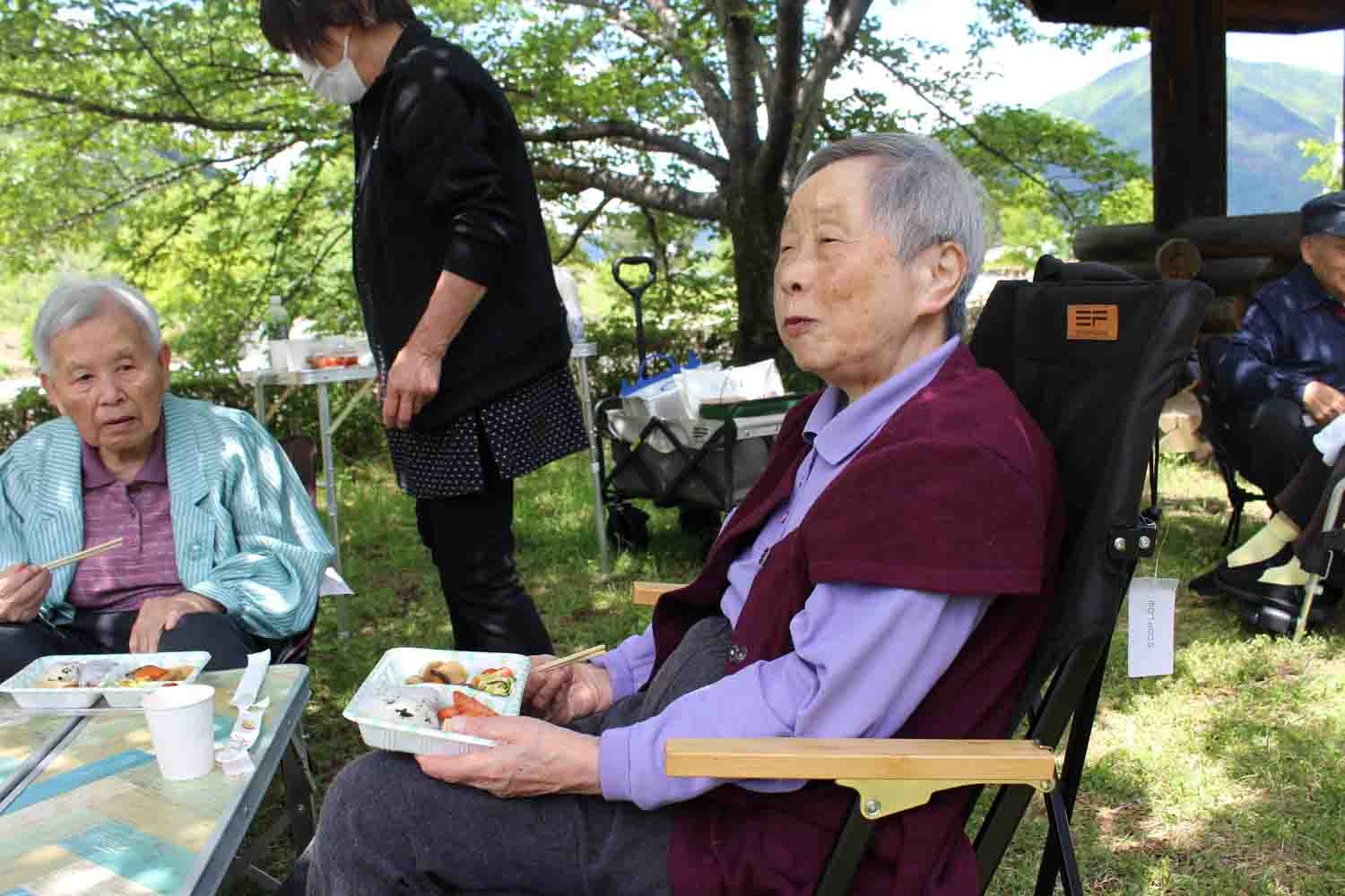 赤いカーディガンを着た入居者さんがおいしそうにご飯を食べています。