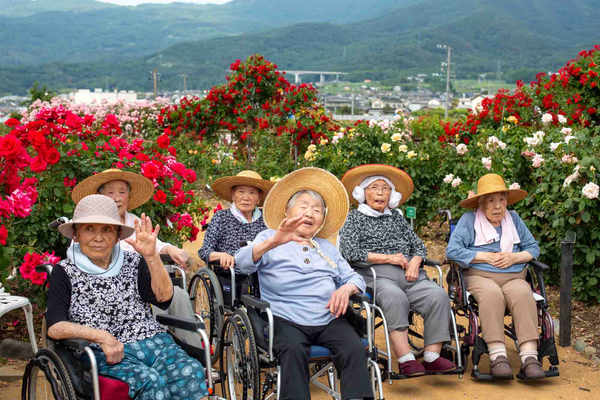 帽子をかぶり、バラの前で集合写真