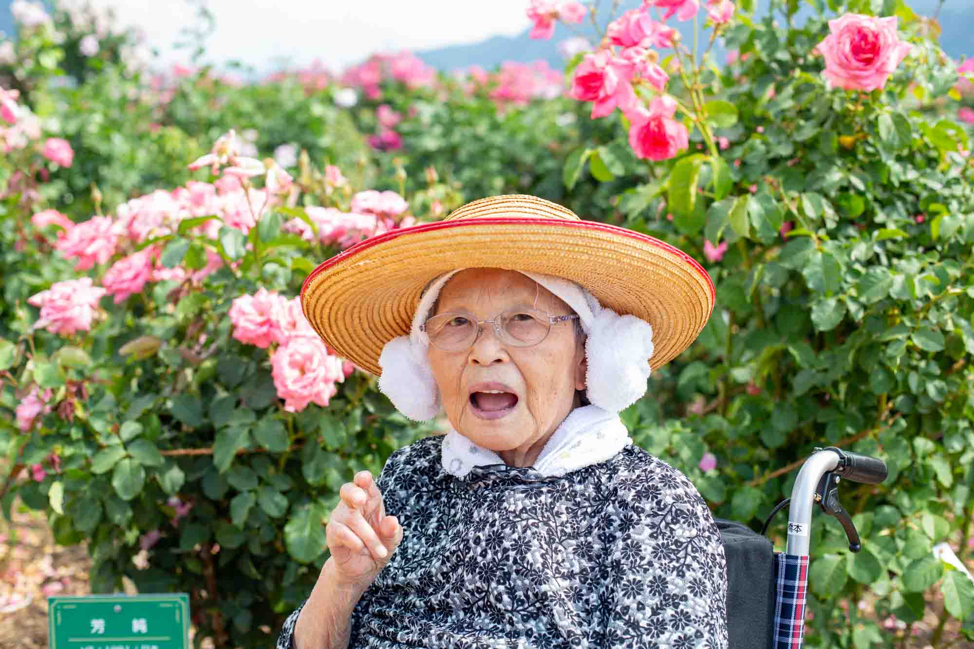 ピンクのバラでひょうきんな顔をする利用者さん