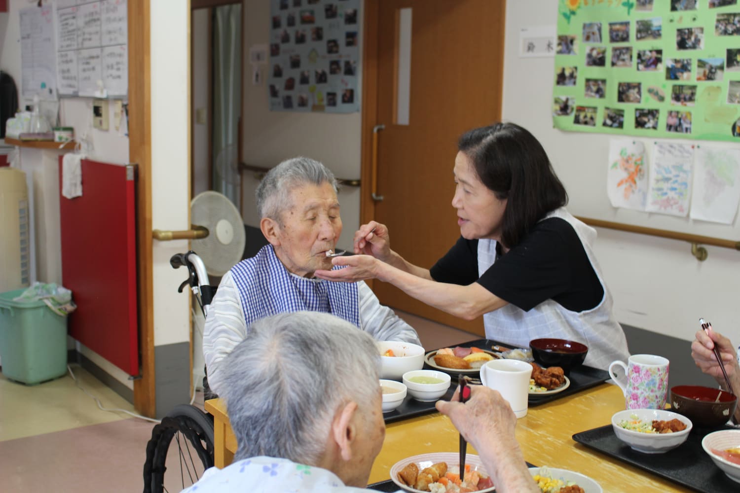 Kさんはスタッフにスプーンで食事介助してもらいながら味わっています。