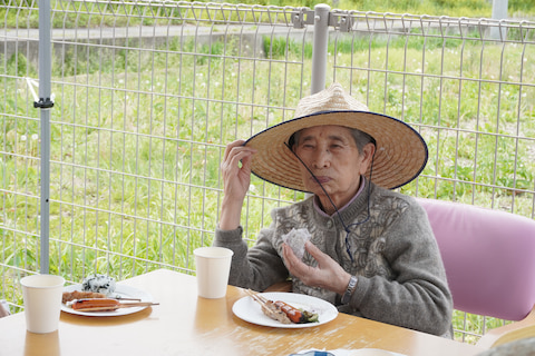 風で飛びそうな麦わら帽子を押さえています。