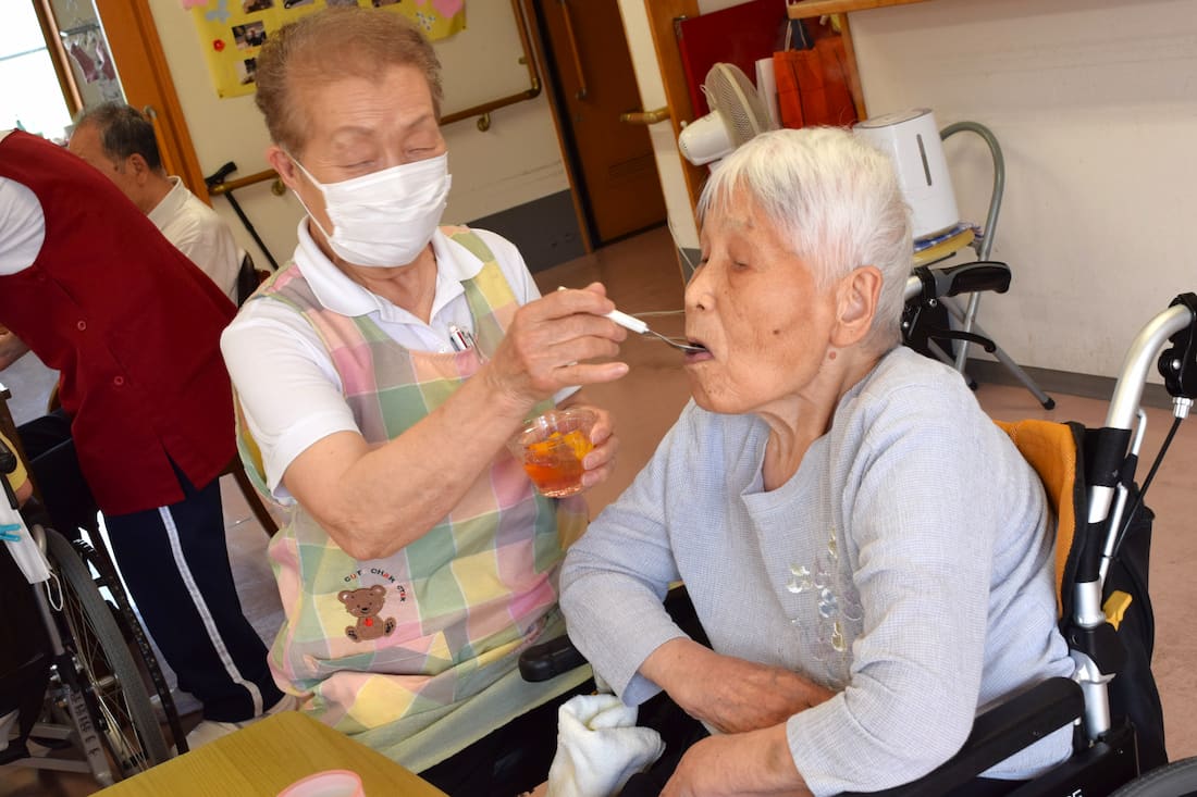 スタッフが、ゼリーを入居者さんの口に運んでいます。