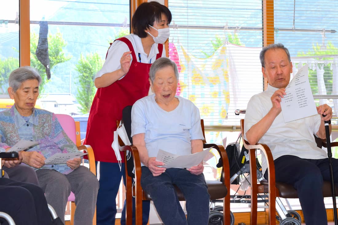 歌詞カードを見ながら歌う入居者さんたち。