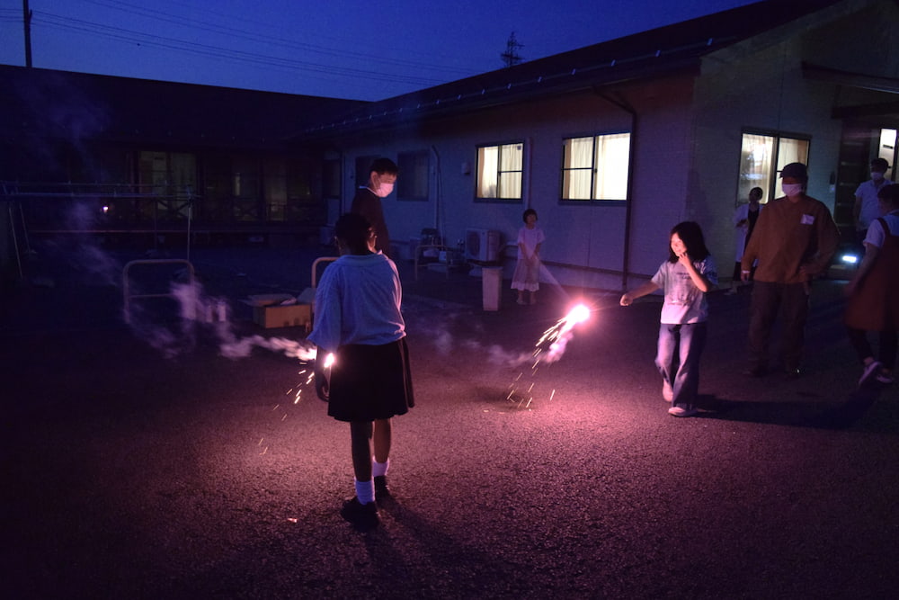 ピンク色の手持ち花火を持って、歩き回る子どもたち。