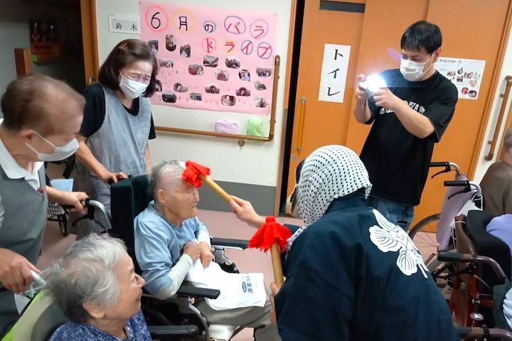棒の先についた赤い布で、入居者さんのおでこをそっと触るひょっとこ