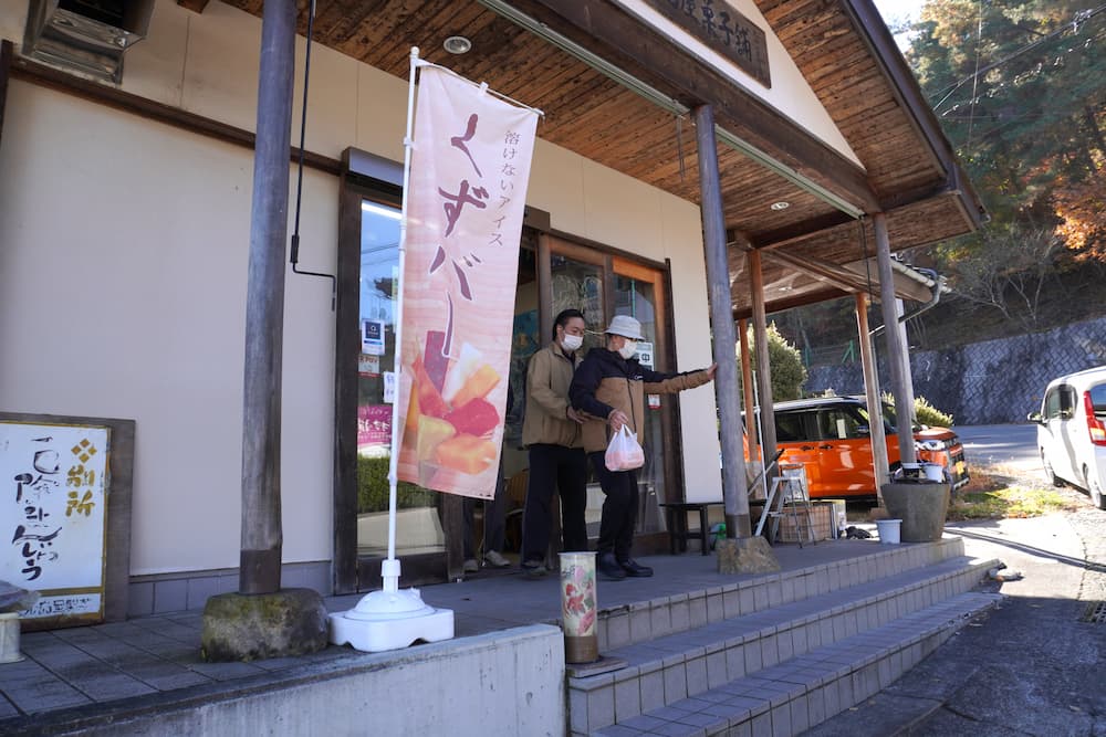 饅頭を片手に、店から出てくる入居者さんとスタッフ