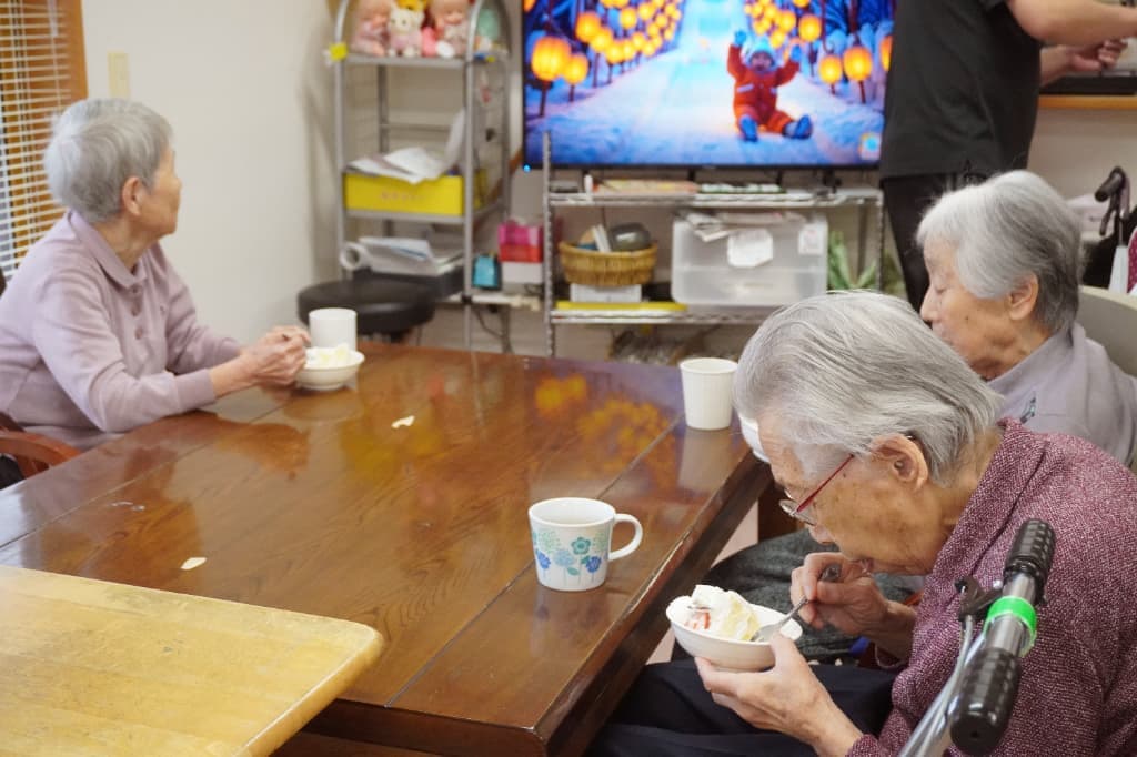 ケーキを食べながら、クリスマスの音楽が流れるテレビを見つめています