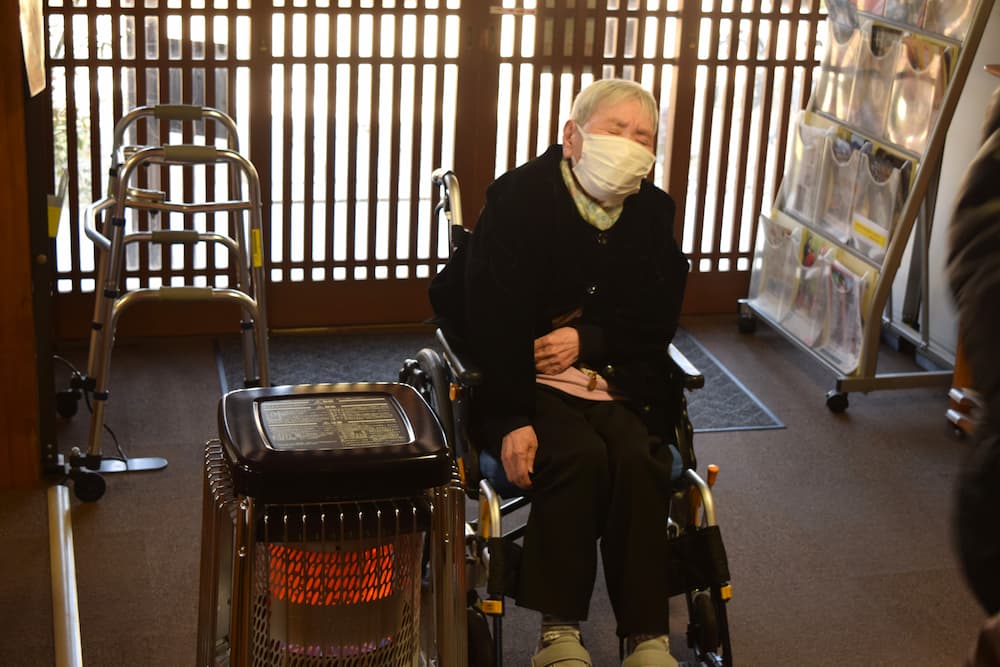 ストーブのそばでうとうとする入居者さん。