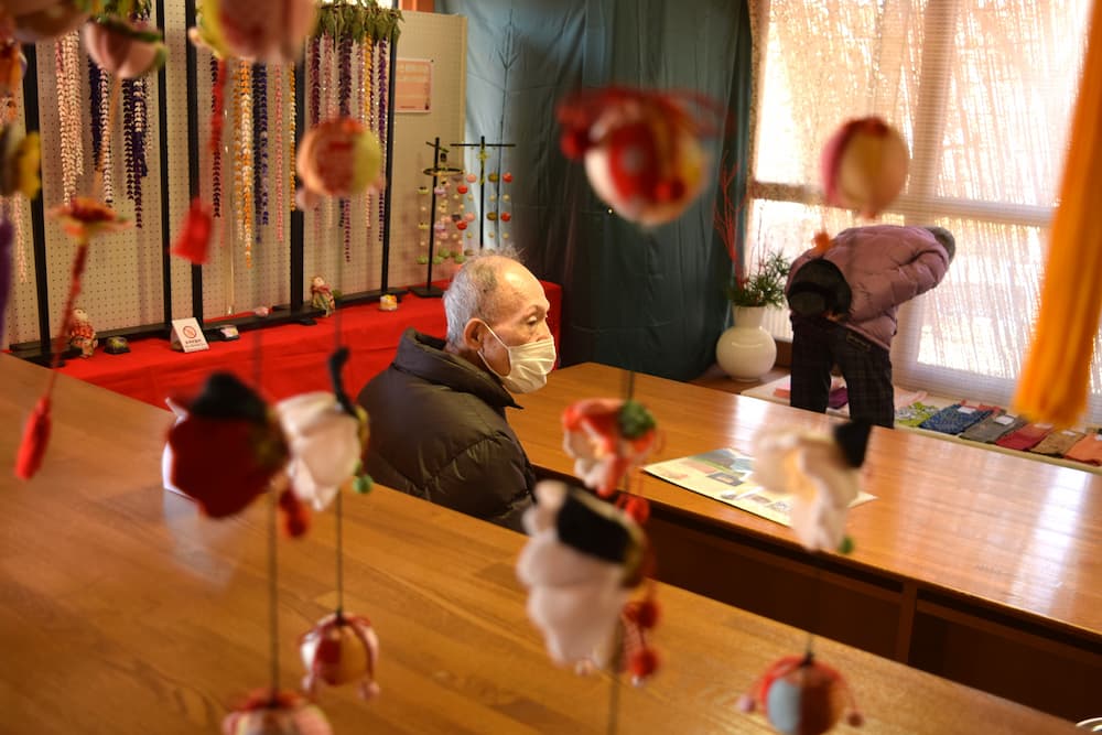 つるし飾りが、座っている入居者さんの後ろで揺れています。